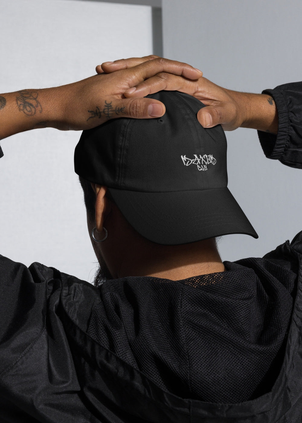 Black urban streetwear cap worn by male model – minimalist unisex accessory with low-profile silhouette and clean fit.