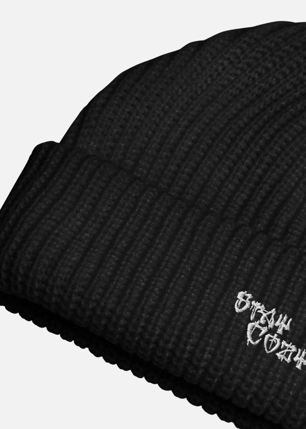 Detail view of black knit streetwear beanie – bold cross embroidery and ribbed texture for urban winter outfits