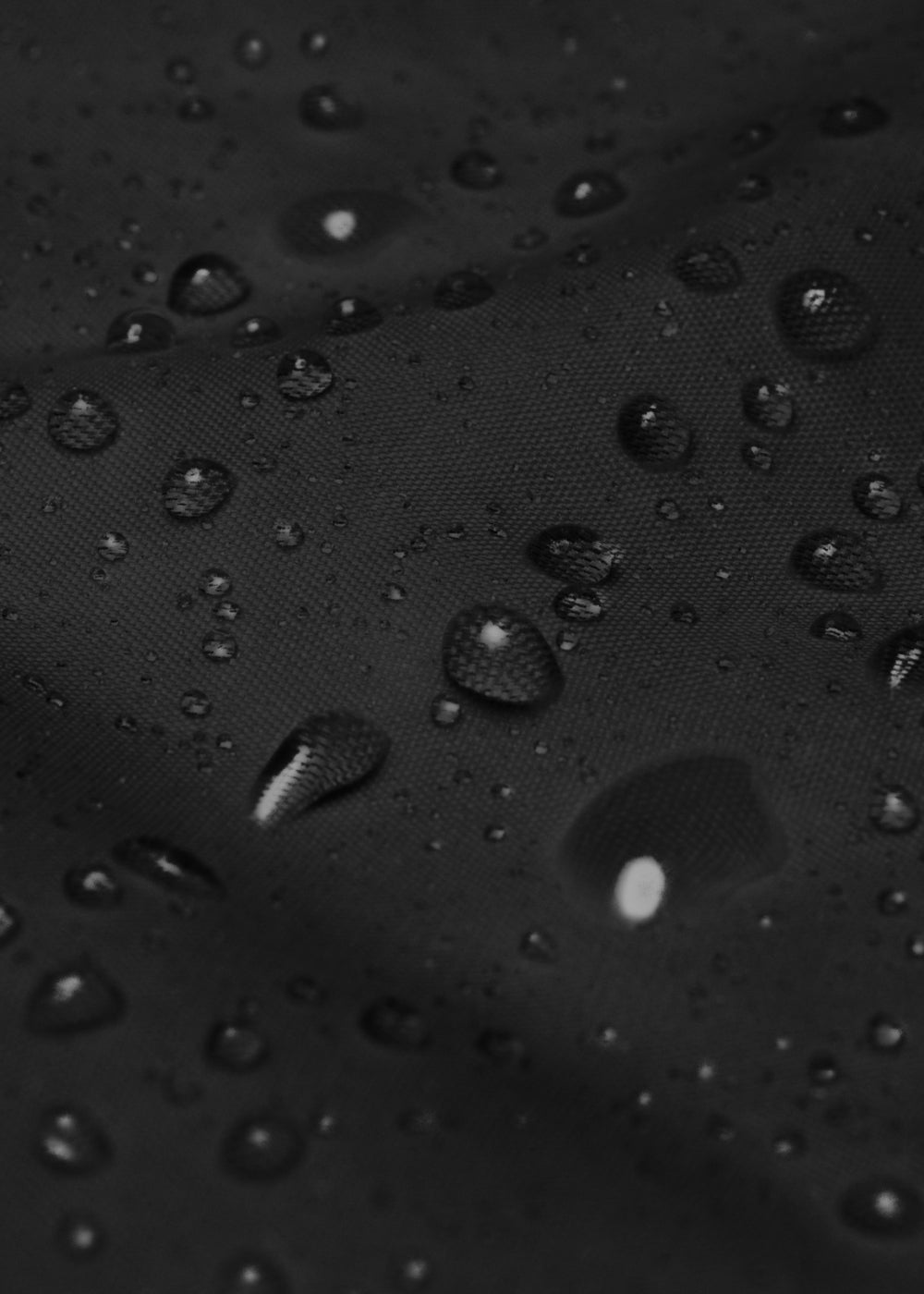 Close-up of black waterproof windbreaker jacket repelling rain – breathable and eco-friendly fabric