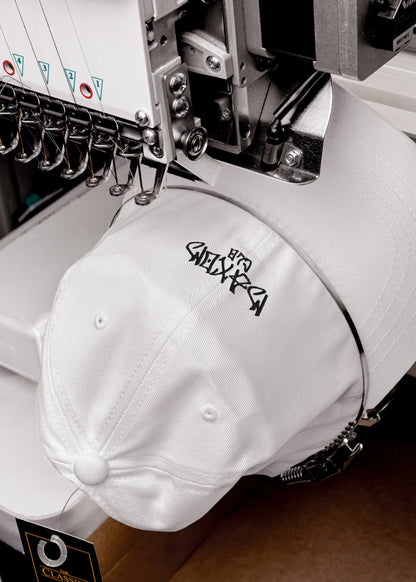 White Skullflow premium low-profile cap being crafted – chino cotton streetwear cap with clean lines and minimal form.


